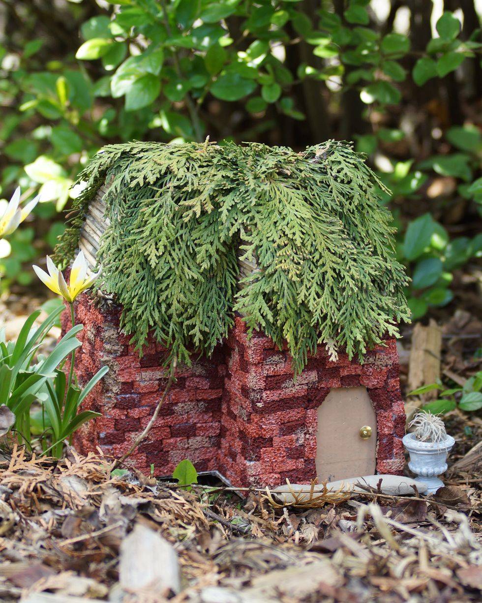 fairy garden house made out of bricks with ceader greenery roof