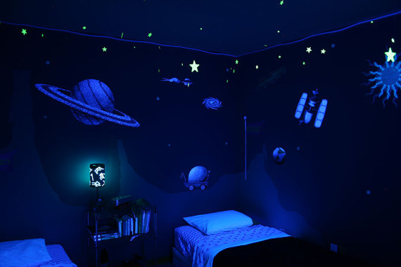 Child bedroom with a space theme, featuring planets, sun, and satellite on the wall paper.