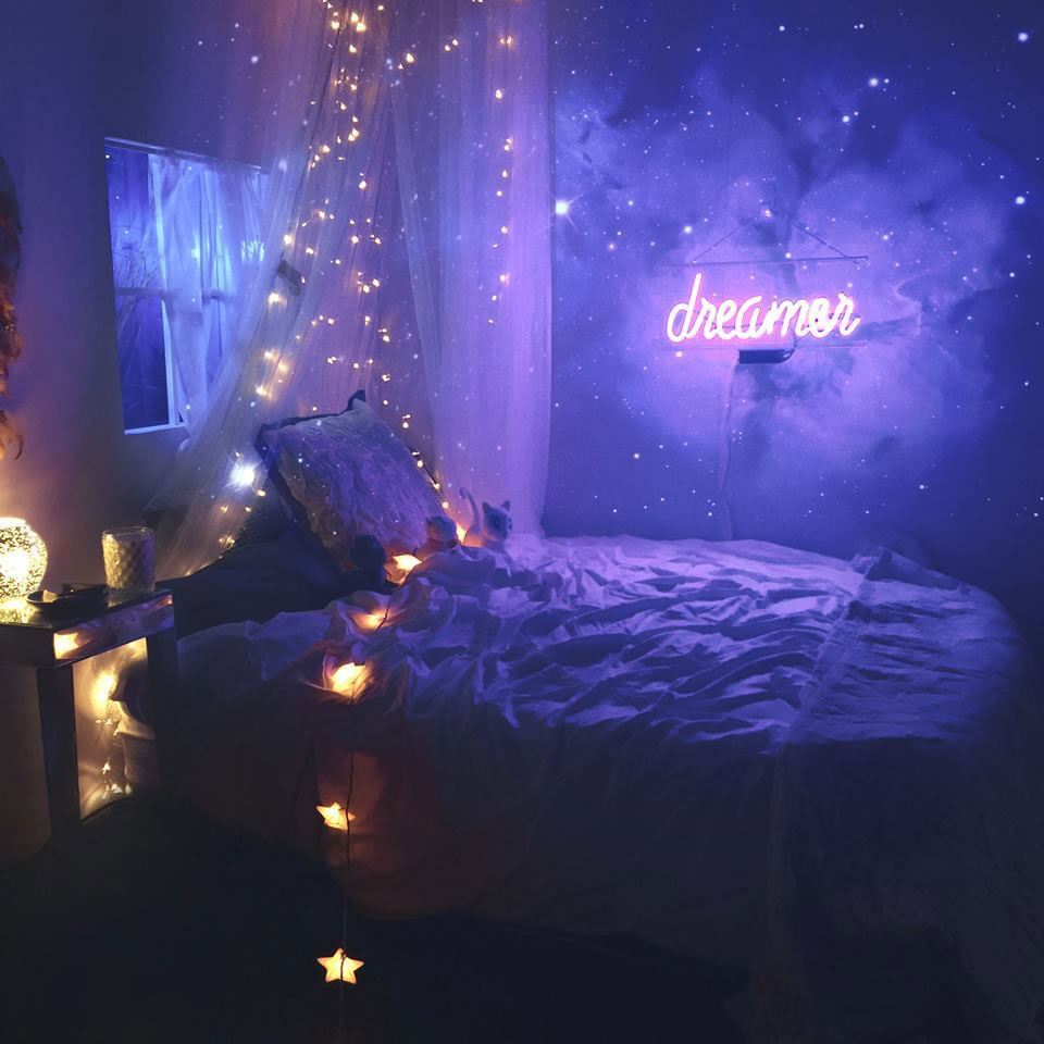 Space children's room with star-themed yellow lights and a bright purple neon sign that reads "dreamer."