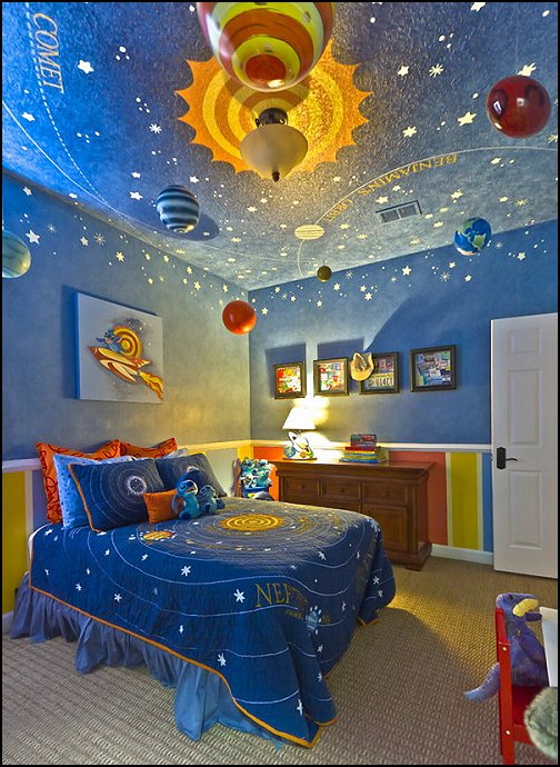 Space children's room is painted blue and has planets hanging from the ceiling.