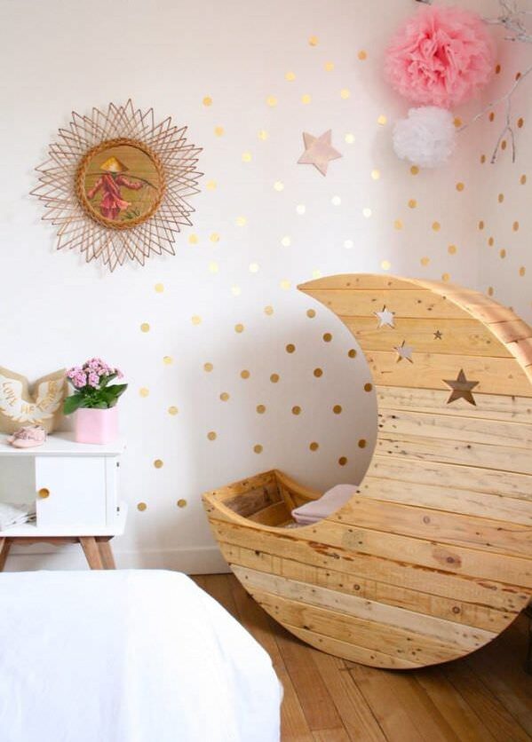 Space-themed nursery with a crescent moon cot flanked by wall decorations.