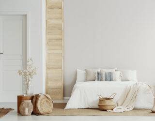 White bedroom interior with natural wooden accents and king size bed, copy space on empty wall